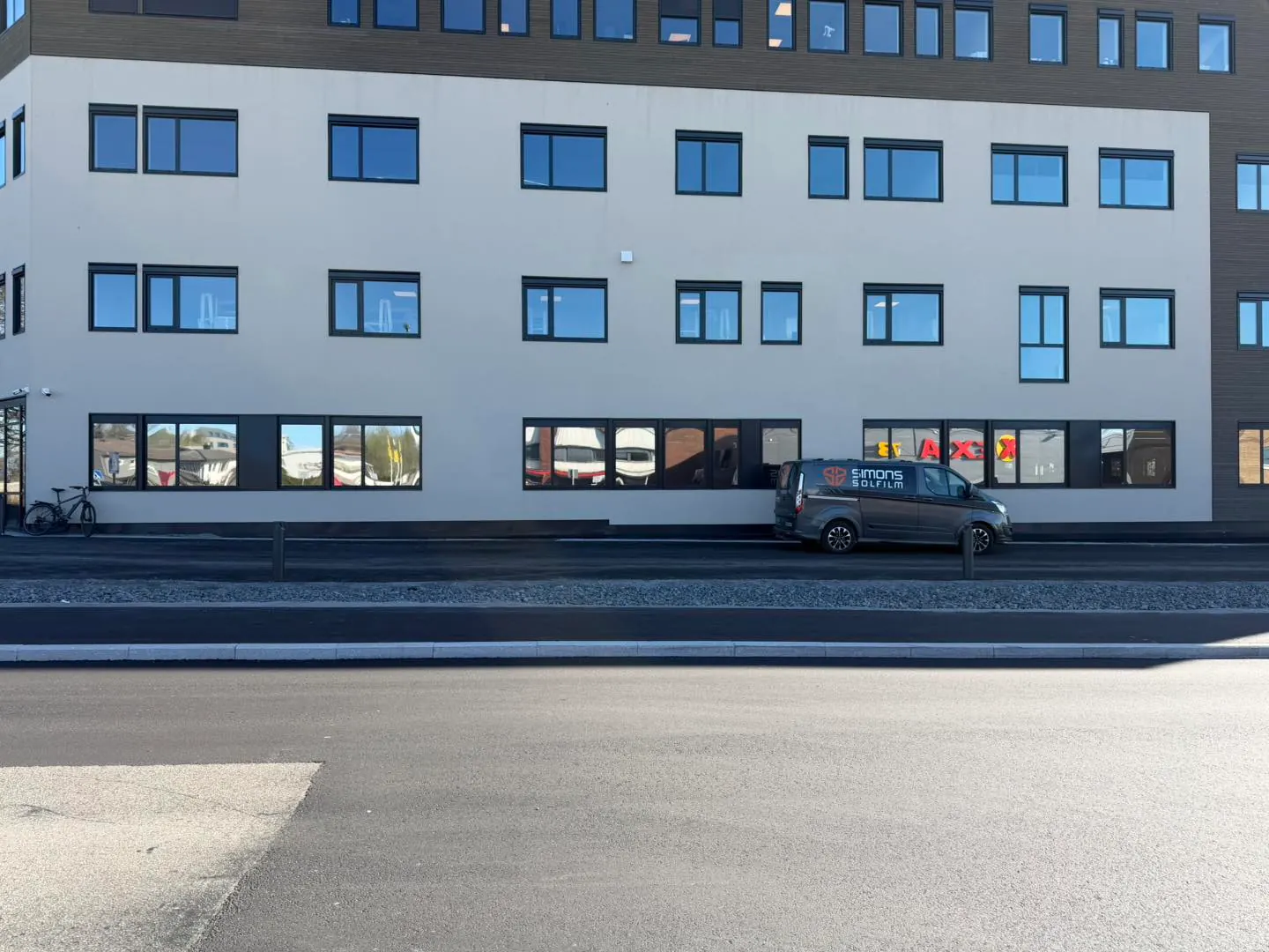 Næringsbygg med solfilm — Simons servicebil parkert foran